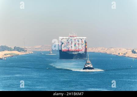 Ismailia, Egypt - November 5, 2017: Large container vessel ship MSC Maya passing Suez Canal in the sandy haze in Egypt. Tugboat accompanies the ships. Stock Photo