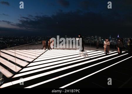 Tokyo, Japan. 15th Oct, 2021. Visitors of Shibuya Sky take photos on the upper floor of the observation deck during sunset.Shibuya Sky is a new attraction for domestic and international tourists with a great view over Tokyo. (Photo by Stanislav Kogiku/SOPA Images/Sipa USA) Credit: Sipa USA/Alamy Live News Stock Photo