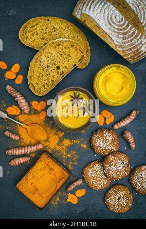 Turmeric golden milk, powder, root, ghee, bread and biscuits on a slate background Stock Photo