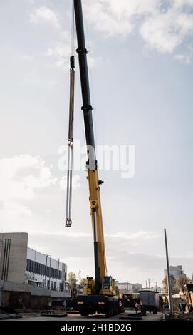 yellow wheeled truck crane stands on construction site . Heavy wheeled loading equipment. Stock Photo