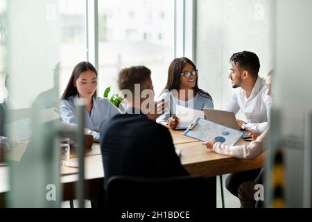 Cheerful Young Multiethnic Business Team Brainstorming Together During Corporate Meeting In Office Stock Photo