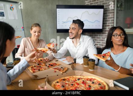Diverse Multiethnic Colleagues Eating Pizza During Lunch Break In Office Stock Photo