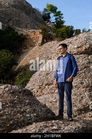 young tourist looking around standing on the rock. survivor looks at the landscape around himself Stock Photo