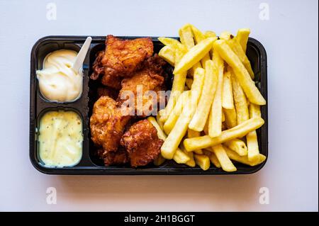 Dutch street food, portion of french fried potatoes, pieces of fried in oil cod fish fillet and two sauces close up Stock Photo