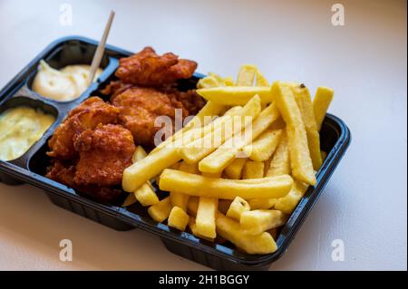 Dutch street food, portion of french fried potatoes, pieces of fried in oil cod fish fillet and two sauces close up Stock Photo