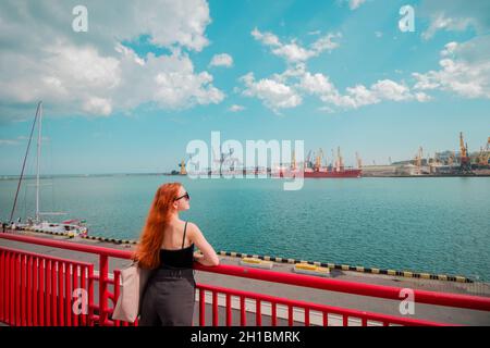 A girl is standing on the pier at the maritime station, waiting for the liner. Stock Photo