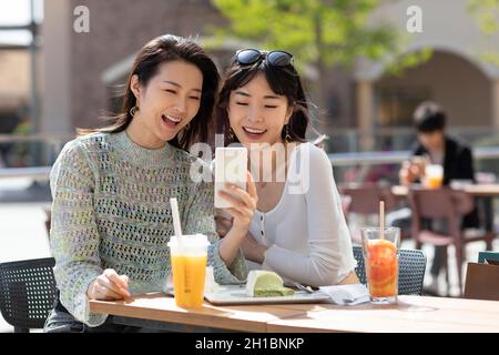 Cheerful best female friends using smart phone Stock Photo