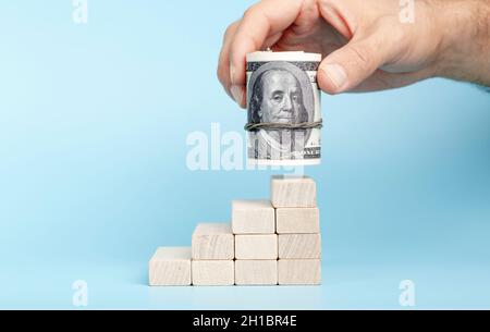 Dollars in hand on a on economic growth on a blue background. International currency and money of the USA. Investment, income, capital, banking, profit and business concept. High quality photo Stock Photo