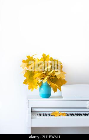 Maple leaves on the piano in a blue vase. The concept of autumn. Front view. Russia. Chekhov. Stock Photo