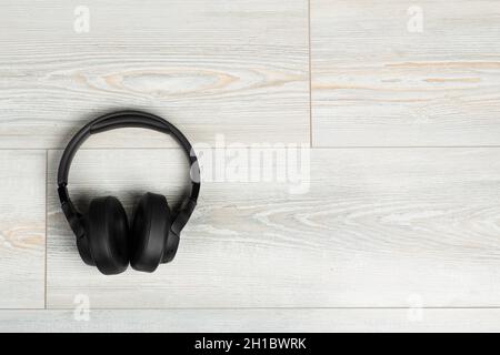 Wireless headphones on a white wooden laminate floor background. Soundproofing, music and sound in the room concept. High quality photo Stock Photo