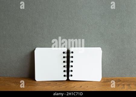 Blank notebook on wooden desk. gray wall background Stock Photo