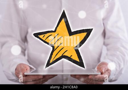 Favorite star concept above a tablet held by a man in background Stock Photo