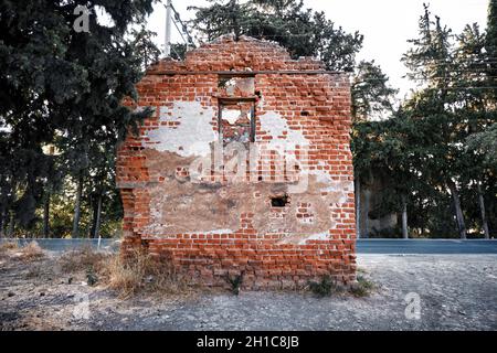 Ruins of an abandoned two-story brick house building exterior in a meadow rural field. Stock Photo