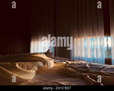 View from a hotel bed at dawn with the curtains shining on them. E-commerce and copy space. Hotel concept 2022. Stock Photo
