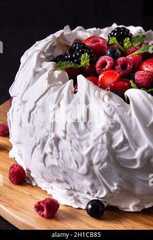 Delicious Pavlova cake with meringue topped and fresh berries on black background Stock Photo