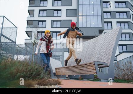 Cheerful young couple owners jumping outdoors in front of new flat, new home and relocation concept. Stock Photo