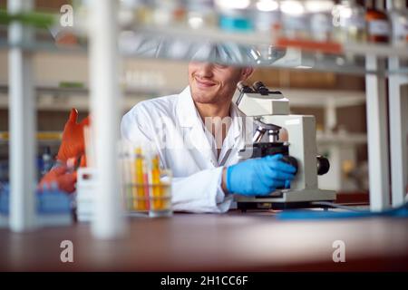 A young male chemistry student enjoying using a microscope in a laboratory in a relaxed atmosphere. Science, chemistry, lab, people Stock Photo