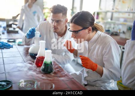 Laboratory workers looking chemical reaction in glassware Stock Photo