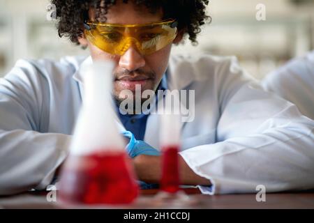 A young male chemistry student observes a chemical in a test tube in a relaxed atmosphere in the laboratory. Science, chemistry, lab, people Stock Photo