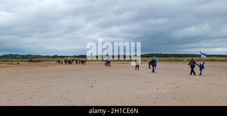 Belhaven Bay, East Lothian, Scotland, UK, 18th October 2021. Cop26 Pilgrimage: after a stopover in Dunbar, Christian climate activists start on the first leg of the John Muir Way and walk across the beach at low tide. The pilgrimage will make its way to COP26 in Glasgow by the end of the month Stock Photo