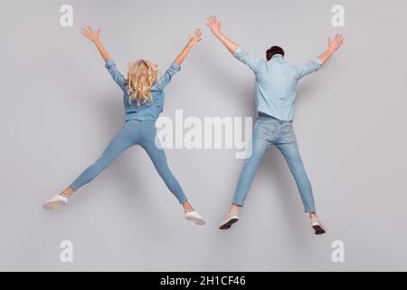 Rear back view photo of couple jump raise hands wear casual jeans outfit isolated grey color background Stock Photo