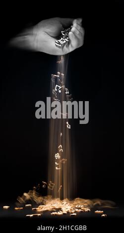 Golden musical notes pouring from the hand, on a black background. The concept of creating,improvisation and playing music Stock Photo