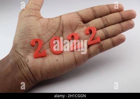 Happy new year wishes concept shown by holding 2022 in hand. A unique way of representing the new year 2022