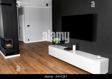 Black matte TV wall in the living room with a standing TV set on a white hanging cabinet. Stock Photo