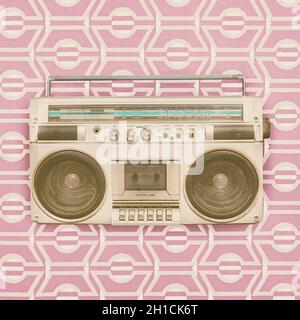 Retro styled image of an eighties portable radio cassette player in front of vintage wallpaper Stock Photo