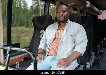 Young contemporary African man sitting on the front double seat while riding by intercity bus Stock Photo