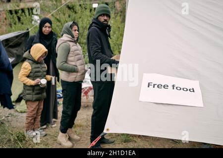Queue of migrants standing in front of volunteering tent to get some free food Stock Photo