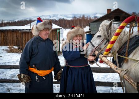 Naryn-Atsagat zone, near Oulan Oude (ulan ude), Siberia, Russia - Mars 09, 2020 : Couple of Buryats  in traditional costumes with their horse. Stock Photo