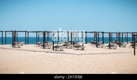 Tavira Island, Portugal - May 3, 2018: View of deckchairs and umbrellas stored on the fine sandy beach sand on a spring day Stock Photo