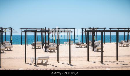Tavira Island, Portugal - May 3, 2018: View of deckchairs and umbrellas stored on the fine sandy beach sand on a spring day Stock Photo