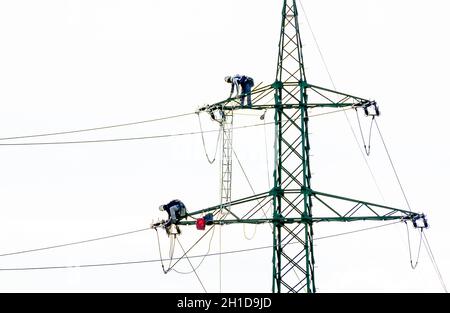 two men working on a tower for the transportation of electric energy Stock Photo