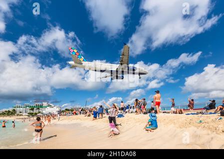 Maho beach, Saint Martin - December 17, 2018: A commercial jet approaches Princess Juliana airport above onlooking spectators. The short runway gives Stock Photo
