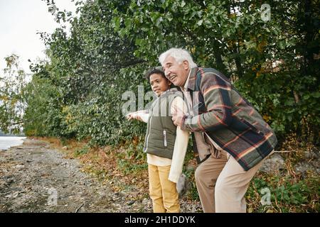 Happy grandfather spending funny time together with his gfrandson in the forest during autumn day Stock Photo