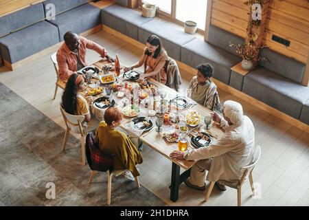 High angle view of big family sitting at dining table and having dinner together in dining room at home Stock Photo
