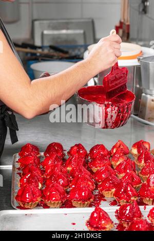 Confectioner makes cakes with fresh strawberries in a tartlet .