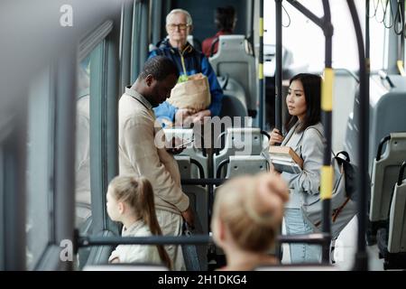 High angle view at young female student holding book on bus while traveling by public transport in city, copy space Stock Photo