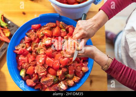 Woman cutting large amount of tomatoes for prepare tomato sauce. Preparation of tomatoes for cooking . Stock Photo