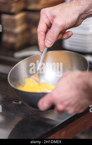 Chef hands beating eggs in a bowl . Stock Photo