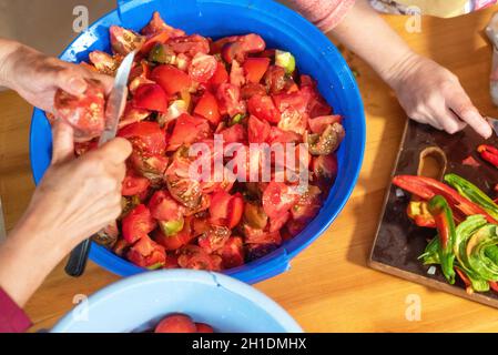Woman cutting large amount of tomatoes for prepare tomato sauce. Preparation of tomatoes for cooking . Stock Photo