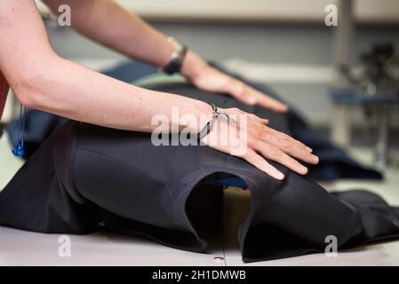 Ironing table. Industrial Presser in sewing suit clothes pressed . Stock Photo