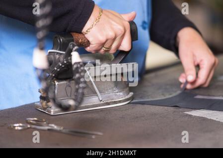 Semstress ironing the fabric. seamstress irons fabirc in a sewing workshop . Stock Photo