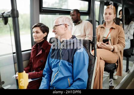 Diverse group of people on seats in public bus commuting in city Stock Photo