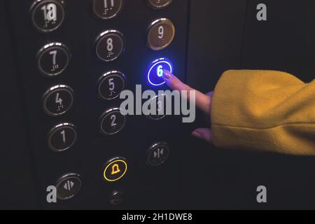 Elevator floor panel in building closeup. Woman hand touch and press the button on the panel with led lights Stock Photo