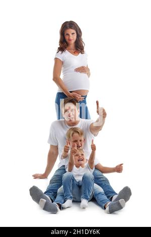Friendly family. Husband with two sons are sitting near pregnant mother, showing sign OK and smiling, isolated on a white background.  Happy parents. Stock Photo