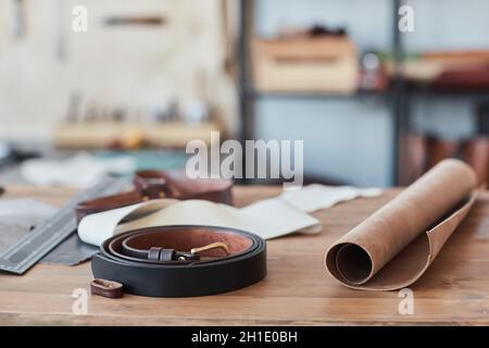 Close up background image of handmade leather belt on wooden table in artisan workshop, copy space Stock Photo