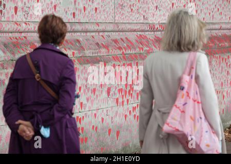 London, UK, 18 October 2021: The National Covid Memorial Wall on the south bank of the Thames, with each heart representing one person who has died during the coronavirus pandemic. So far the total number of people in the UK who have died with Covid-19 on their death certificates is 161,798. The wall is boundary of St Thomas's Hospital and faces the Houses of Parliament, with the hearts stretching for hundreds of metres besides the River Thames. It was created by volunteers organised by the campaign group Covid-19 Bereaved Families for Justice with the help of Led By Donkeys. The original red